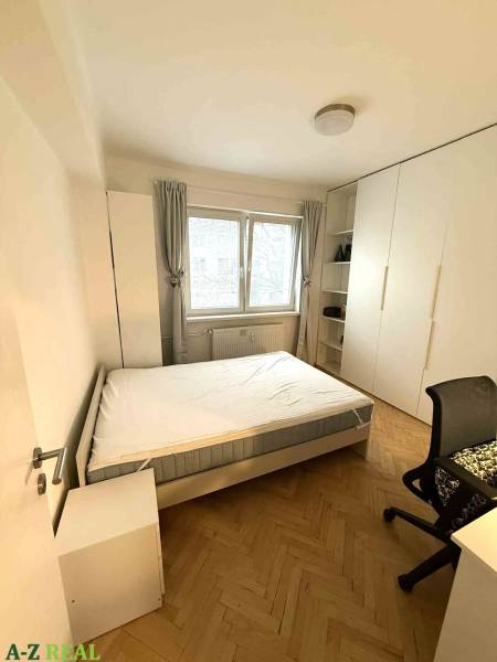 Schlafzimmer in einer 4-Zimmer-Wohnung mit Bett, Schrank und Boden in Holzoptik.