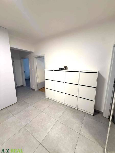 Ein geräumiger Flur mit hellen Fliesen und einer weißen Kommode in einer 4-Zimmer-Wohnung.