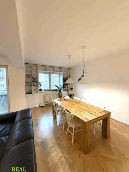 Esstisch in einer 4-Zimmer-Wohnung mit Holzboden und weißen Stühlen.