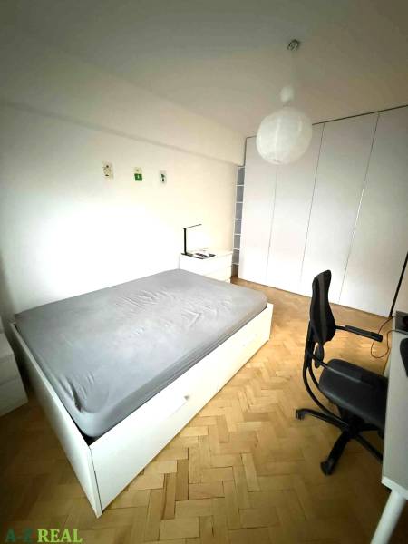 Schlafzimmer mit Einbauschränken, Holzboden und einfacher Möblierung in einer Vierzimmerwohnung.