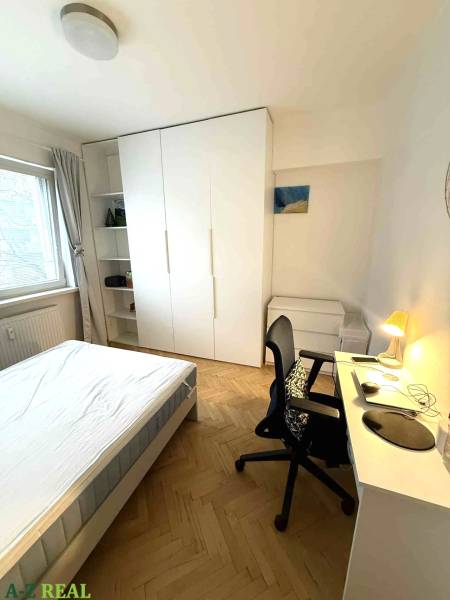 Schlafzimmer in einer 4-Zimmer-Wohnung mit weißen Möbeln und einem Boden in Holzoptik.