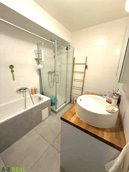 Badezimmer mit Badewanne, Dusche und Waschbecken auf einer Holzplatte in einer 4-Zimmer-Wohnung.