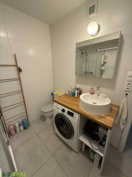 Badezimmer mit Dusche, Waschbecken, Waschmaschine und WC in einer 4-Zimmer-Wohnung.