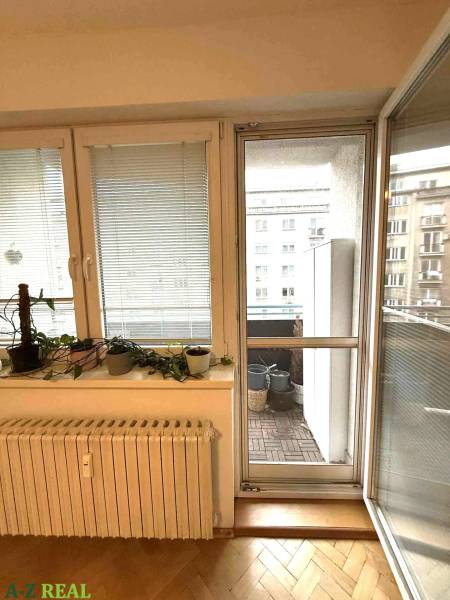 Innenraum einer 4-Zimmer-Wohnung mit Holzboden und Zugang zum Balkon.