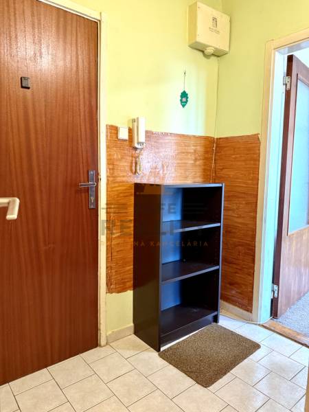 Eingangsflur einer Einzimmerwohnung mit Schrank, Fliesen und Telefon an der Wand.