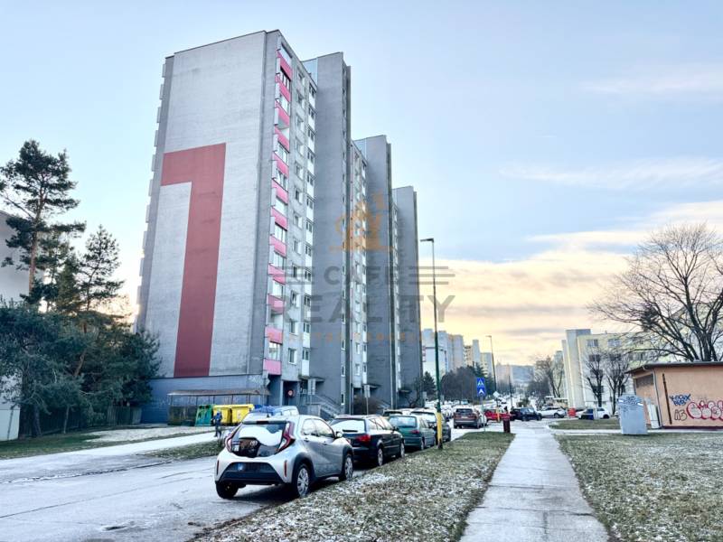 Ein Wohnblock in der Drobného-Straße in Bratislava - Dúbravka, umgeben von Autos und Grünflächen.