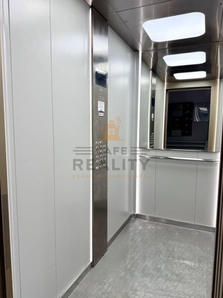 Der Innenraum des Aufzugs mit einer Edelstahlplatte und einem Spiegel in einer Einzimmerwohnung.