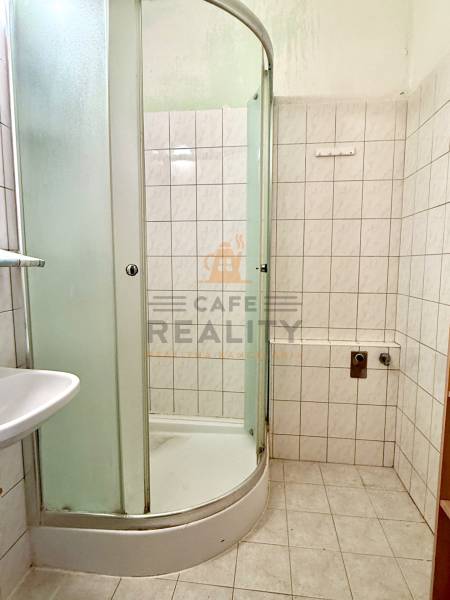 Badezimmer mit Dusche und Fliesen in einer Einzimmerwohnung.