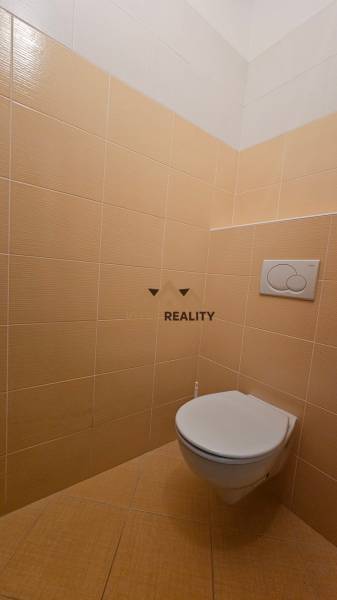 Toilette mit beigefarbenen Fliesen in Geschäftsräumen.