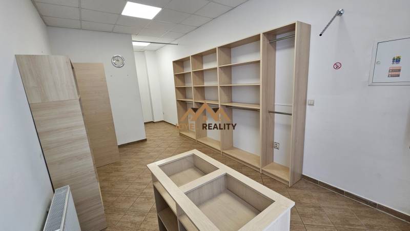 Geschäftsräume mit Regalen und einem Boden in Holzoptik, weiße Wand, Deckenbeleuchtung.