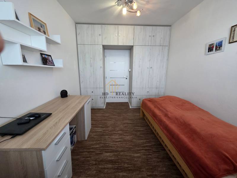 Innenraum einer 3-Zimmer-Wohnung mit Bett, Schreibtisch und Einbauschrank.