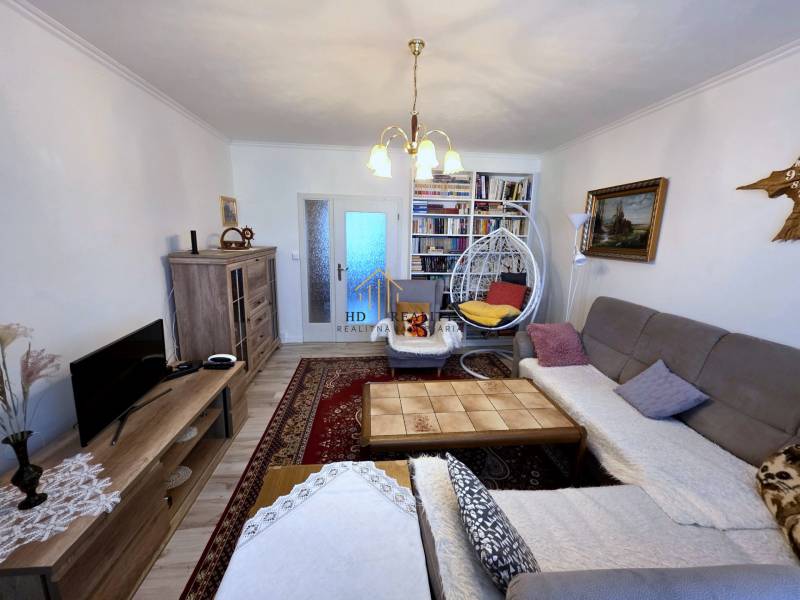 Wohnzimmer in einer 3-Zimmer-Wohnung mit Holzboden und Bücherregalen.