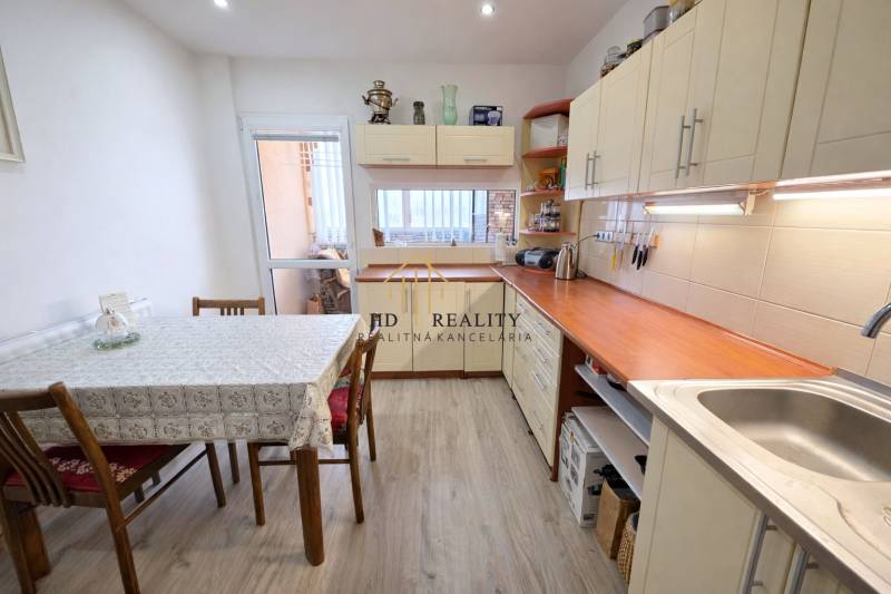 Küche in einer 3-Zimmer-Wohnung mit weißen Möbeln und einem Boden in Holzoptik.