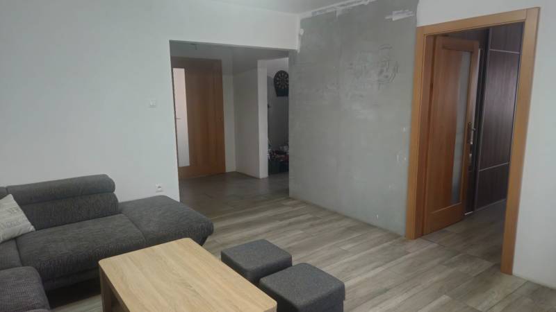 Wohnzimmer in einem Einfamilienhaus, graues Sofa, hölzerner Couchtisch, Boden mit Holzdekor.