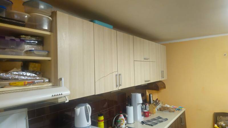 Küche in einem Einfamilienhaus mit Holzschränken und Zubehör auf der Küchenarbeitsplatte.