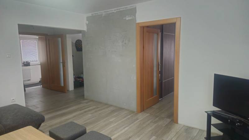 Innenraum eines Einfamilienhauses mit Holzboden, Fernseher und offenen Türen.