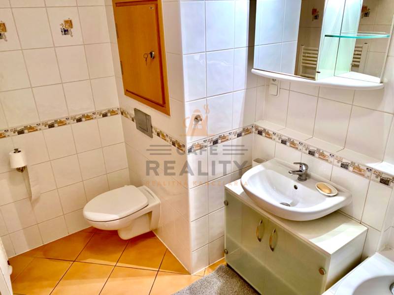 Badezimmer in einer 2-Zimmer-Wohnung mit Keramikfliesen und hellen Möbeln.