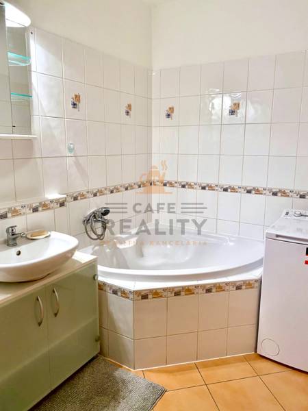 Badezimmer mit Fliesen, Badewanne und Waschmaschine in einer 2-Zimmer-Wohnung.