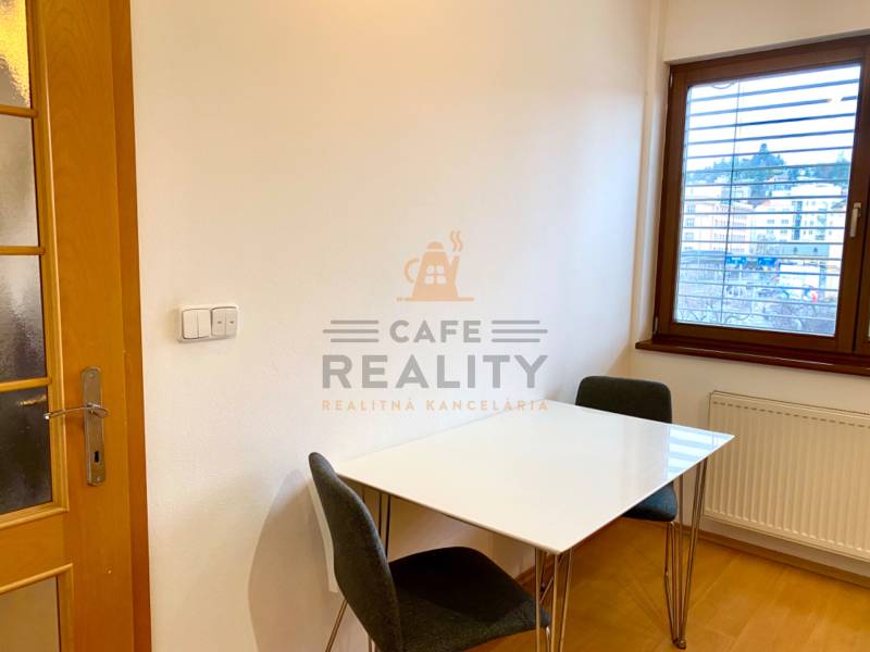 Essbereich mit weißem Tisch und Stühlen in einer 2-Zimmer-Wohnung, Boden mit Holzdekor.