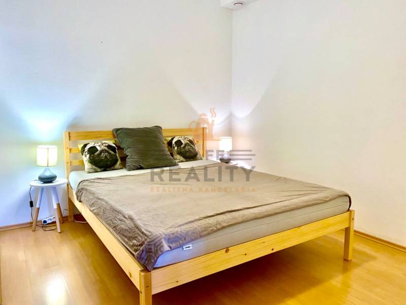 Schlafzimmer in einer 2-Zimmer-Wohnung mit Holzelementen und Kissen auf dem Bett.