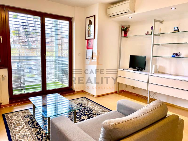 Wohnzimmer in einer 2-Zimmer-Wohnung mit Sessel, Glastisch und Boden in Holzoptik.