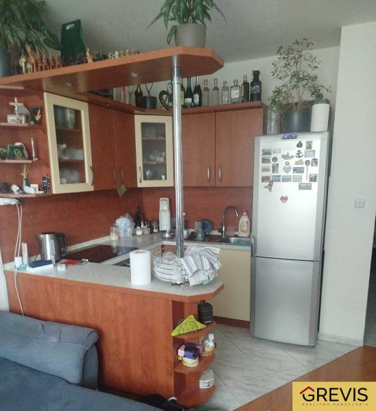 Kompakte Küche in einem Einzimmerapartment mit Eckküche, Kühlschrank und Regalen.