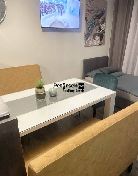 Wohnbereich mit Fernseher in einem Einfamilienhaus, Glastisch, Sofas, Pfauenbild, Boden mit Holzdekor.