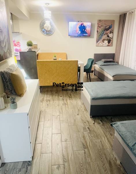 Wohnbereich in einem Einfamilienhaus mit Sofa, Sessel, Fernseher und Boden mit Holzdekor.