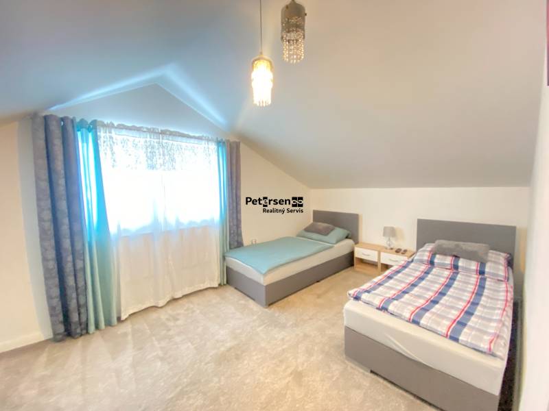 Ein Dachzimmer mit zwei Betten und einem weichen Teppich in einem Einfamilienhaus.