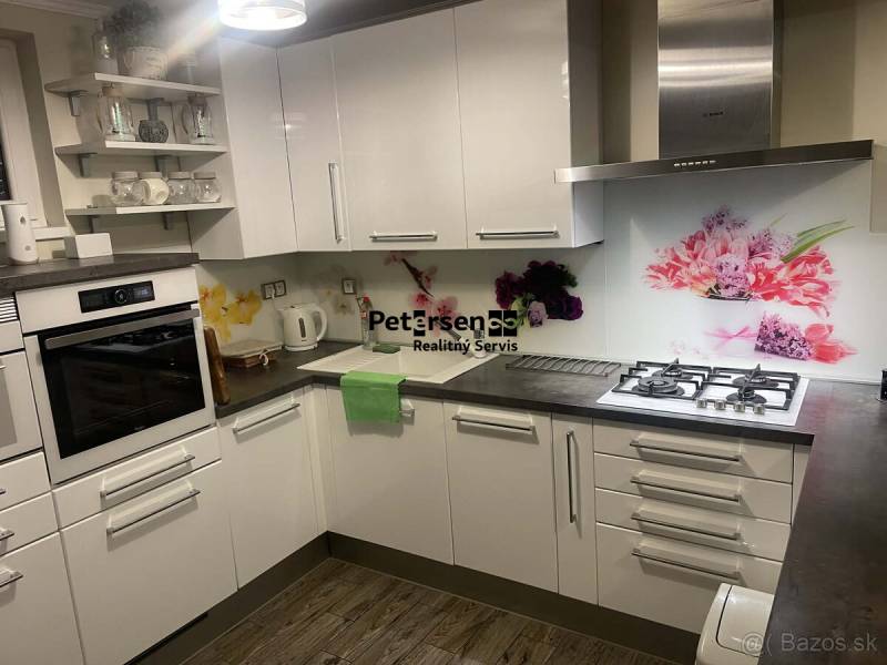 Küche in einem Einfamilienhaus mit weißen Schränken, dekorativen Fliesen und einem Boden mit Holzdekor.