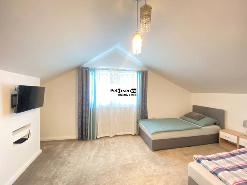 Schlafzimmer im Einfamilienhaus mit zwei Betten, Fernseher und Teppichboden.