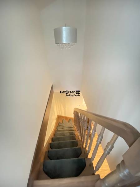 Eine Treppe mit Teppich führt nach oben, darüber hängt eine Leuchte in einem Einfamilienhaus.