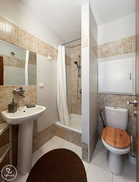 Badezimmer mit Dusche, Waschbecken und Toilette in einer Einzimmerwohnung.