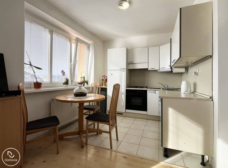 Küche in einer Einzimmerwohnung mit rundem Tisch und Holzboden.