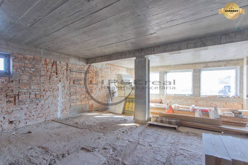 Baustelle in einem Gebäude mit Ziegelwänden und großen Fenstern. Der Bau befindet sich im Bauzustand.