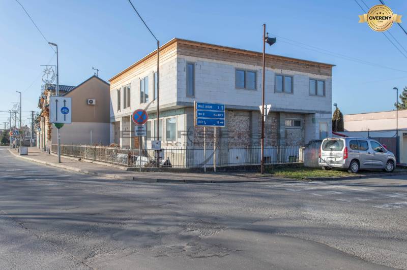 Ein Gebäude in Veľké Leváre, an der Straße, mit einem geparkten Auto und Verkehrsschildern.