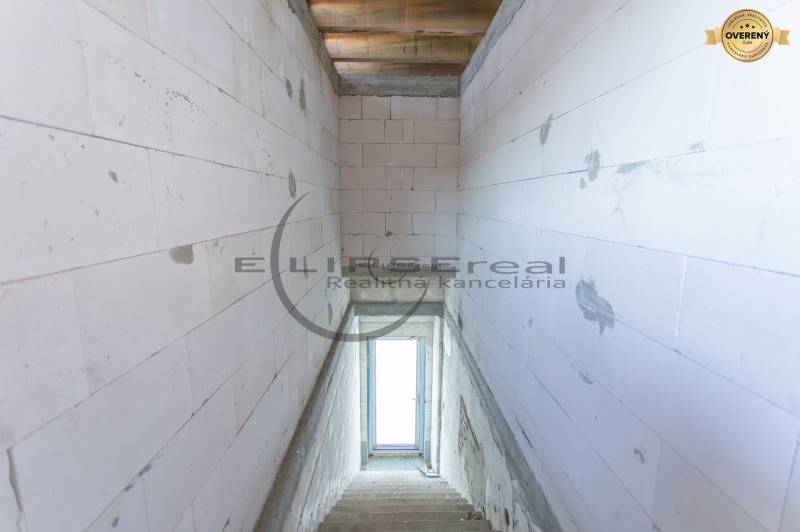 Ein Blick auf die Treppe in einem Gebäude mit Betonwänden und einem Fenster am Ende.