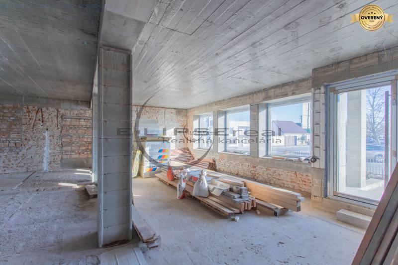 Innenraum eines Gebäudes mit Ziegelwänden, großen Fenstern und Baumaterial.