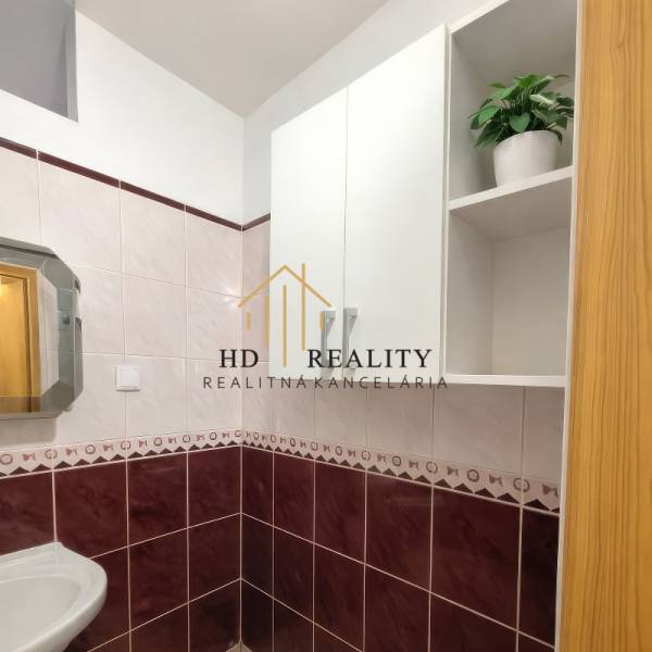 Badezimmer in einer 2-Zimmer-Wohnung mit Keramikfliesen und einem Spiegel über dem Waschbecken.