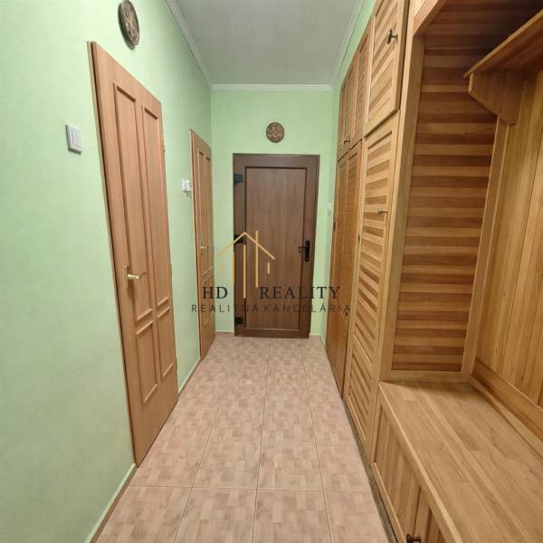 Flur in einer 2-Zimmer-Wohnung mit Holzelementen und grünen Wänden.