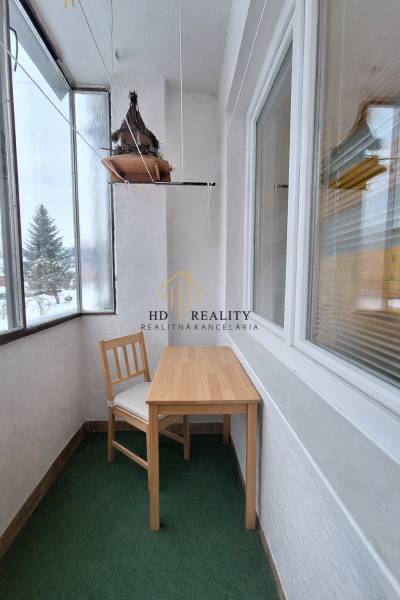 Veranda mit Glasfenstern mit einem Holztisch und einem Stuhl in einer 2-Zimmer-Wohnung.