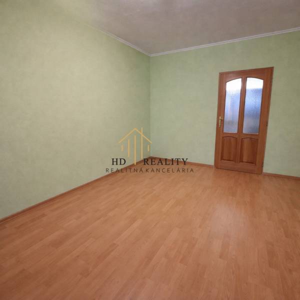 Ein leerer Raum mit Holzboden und grünen Wänden in einer Zweizimmerwohnung.