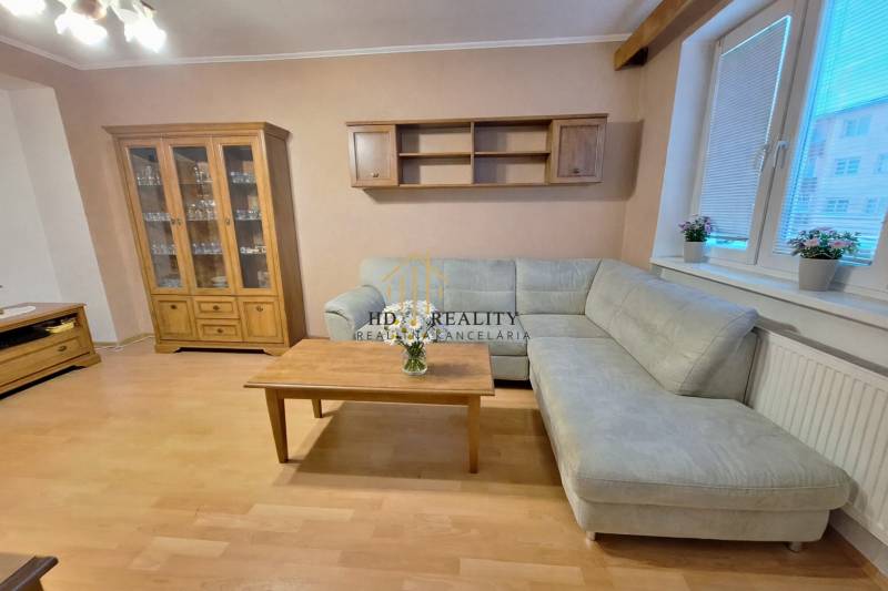 Wohnzimmer in einer 2-Zimmer-Wohnung mit Ecksofa, Holzelemente ergänzen das Interieur.