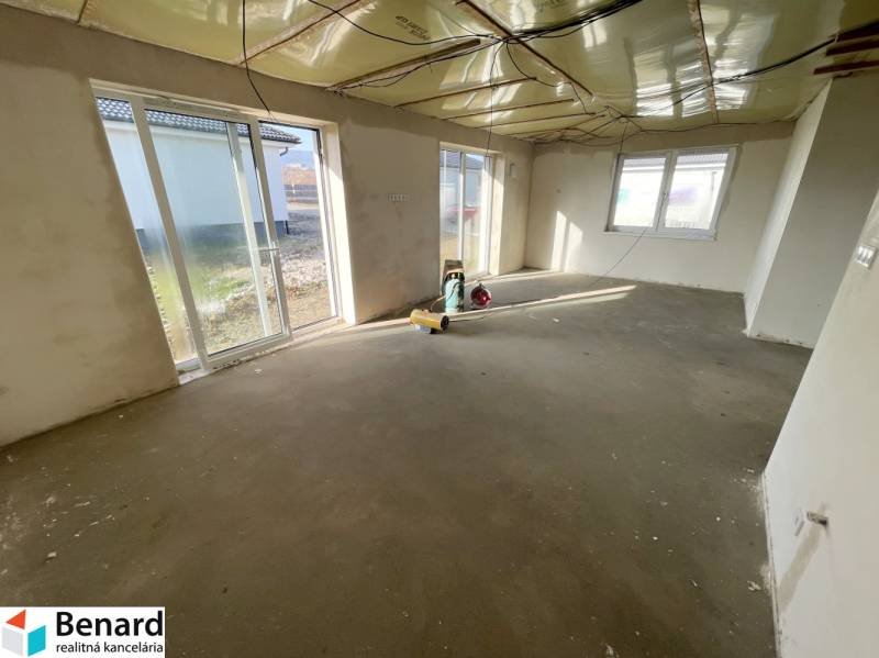 Ein geräumiger Raum in einem Einfamilienhaus mit rohem Betonboden, große Fenster bieten ausreichend Licht.