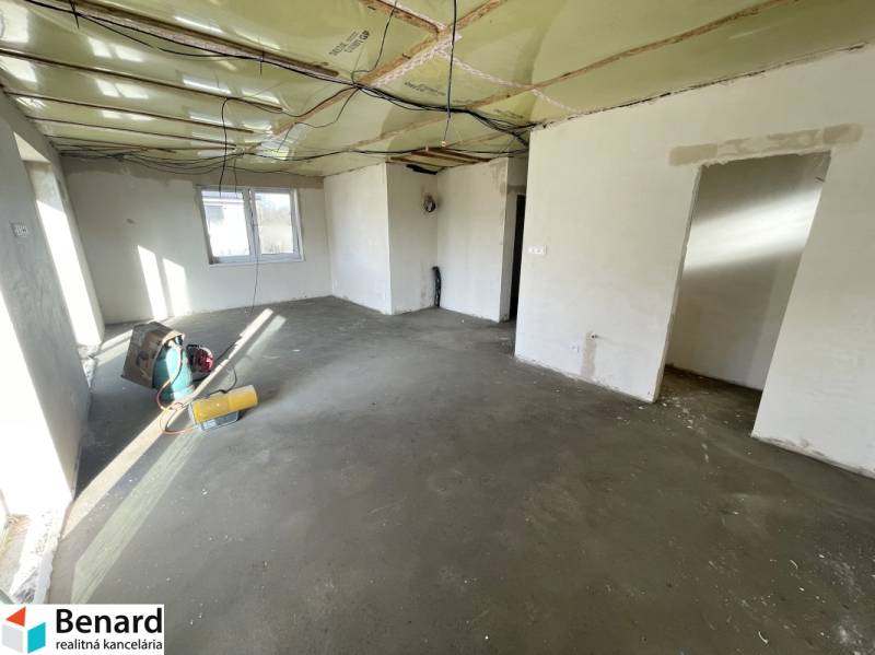 Innenraum eines Einfamilienhauses mit unfertigem Boden und unvollendeter Decke.