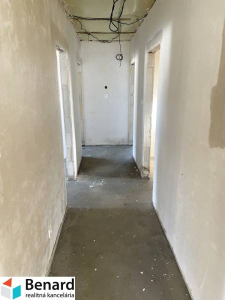 Der Flur eines Einfamilienhauses mit einer unbehandelten Decke und einem Betonboden.