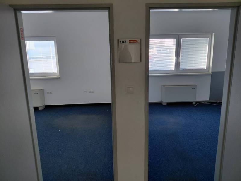 Innenraum von Büros mit blauem Teppichboden und Fenstern mit Jalousien.