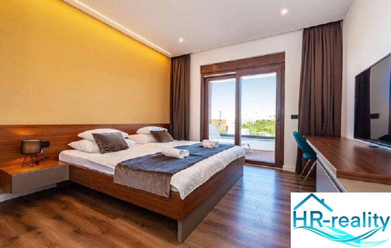 Elegantes Schlafzimmer in einer Villa mit Bett und Boden in Holzoptik.