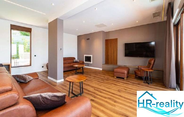 Wohnzimmer in einer Villa mit Holzboden, Ledersofa und Fernseher.