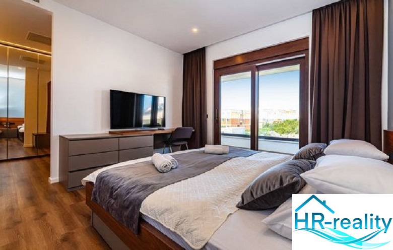 Ein stilvolles Schlafzimmer mit einem großen Bett, einem Fernseher und einem Boden mit Holzdekor in der Villa.